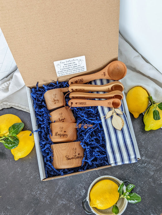 gift box containing- measuring cups, measuring spoons, dishtowel, and lemon shaped wooden magnet 